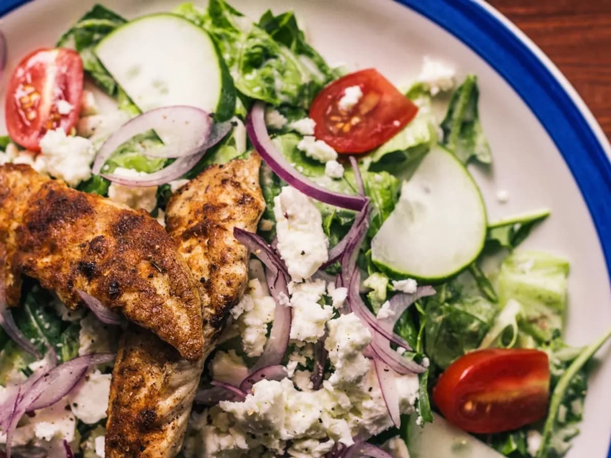 Grilled chicken over a salad with feta, cucumber and tomato